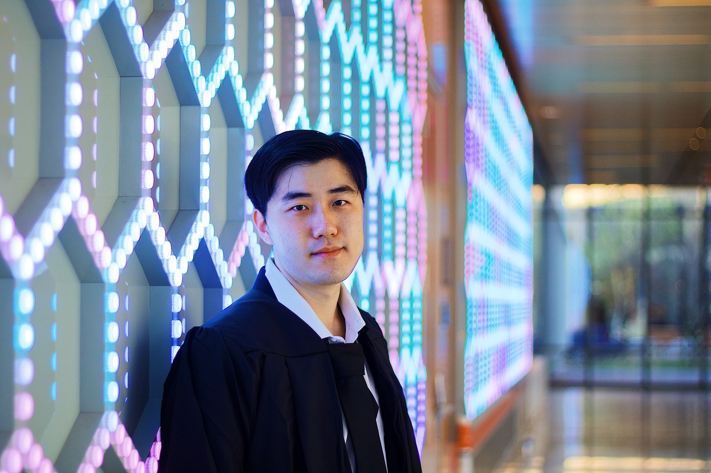 Graduate photographed against a glowing LED wall