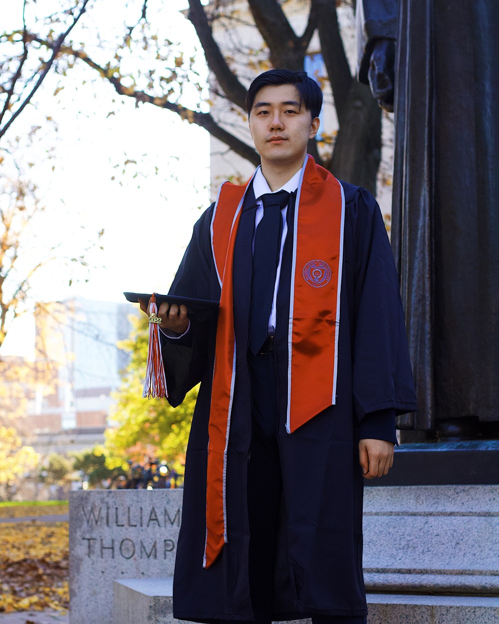 Graduate standing before glass library stacks